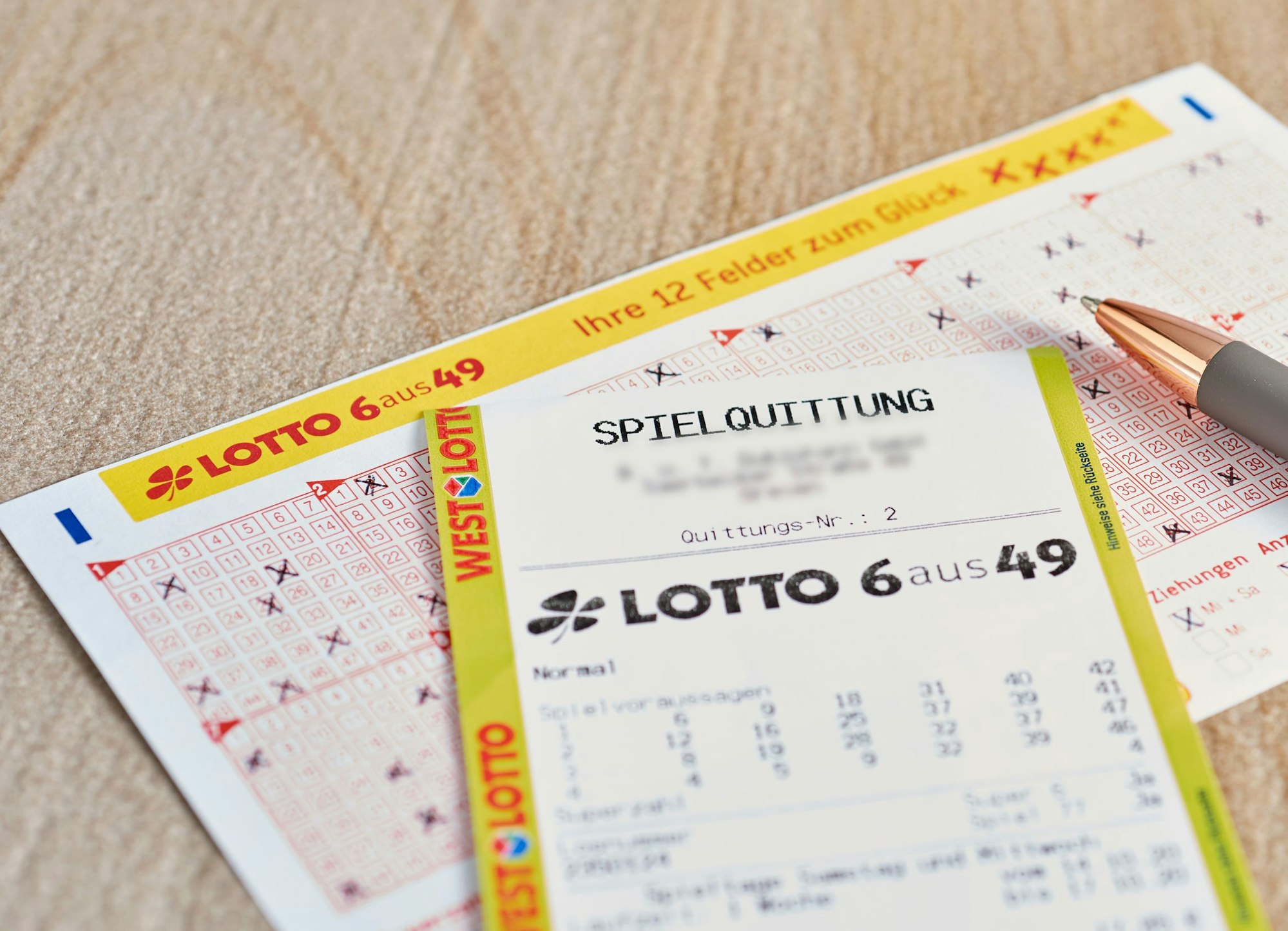 Ein Lotto 6aus49 Tippschein und ein Los liegen auf dem Tisch.