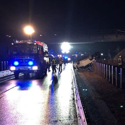 Feuerwehrleute und Polizisten stehen an dem Auto auf der A44, das mutmaßlich wegen gestohlener Warnschilder und Absperrungen von einer demontierten Autobahnbrücke gestürzt ist.