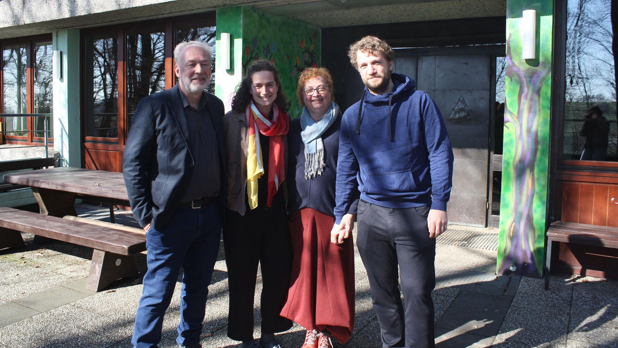 Die Familie steht vor dem Eingang eines Hauses und schaut in die Kamera.