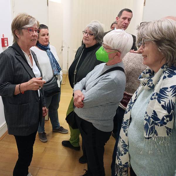 Die Künstlerin Gerda Laufenberg steht links und spricht angeregt mit Besuchern.