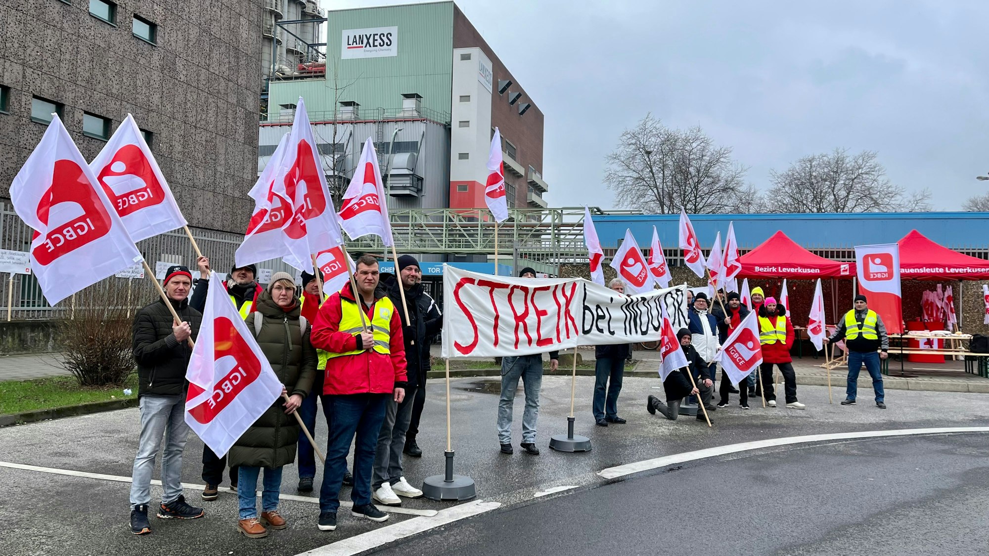 Mit einem Transparent stehen die Beschäftigten von Indulor vor Tor 4 des Chempark. Sie streiken.