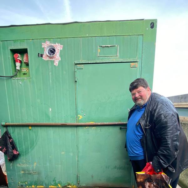 Klaus Berg an der Tür zu seinem Zuhause, er schaut in die Kamera, hinter sich eine grüne Containerwand.