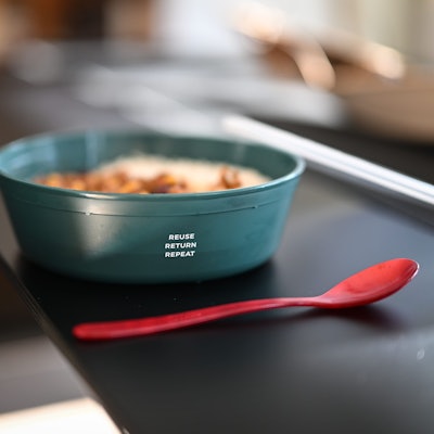 Eine Mehrwegschüssel der Marke Rebowl steht mit Essen gefüllt auf einem Tisch.