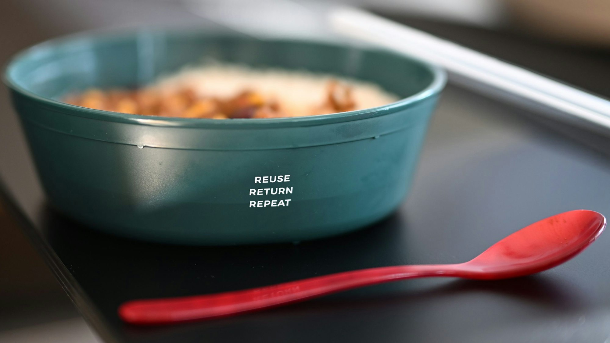 Eine Mehrwegschüssel der Marke Rebowl steht mit Essen gefüllt auf einem Tisch.