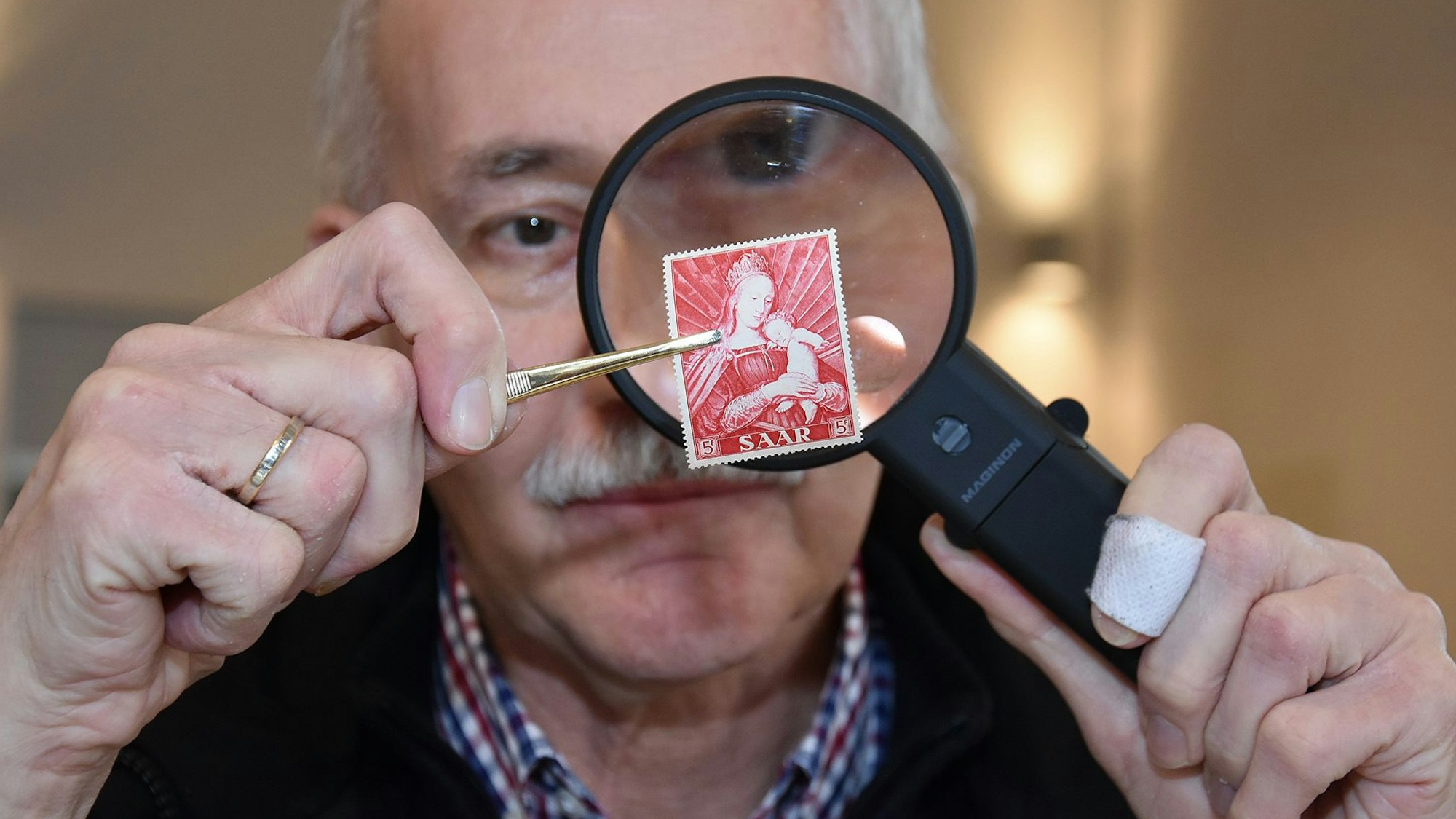 Der Sammler Friedrich Dörre nimmt eine Briefmarke unter die Lupe.