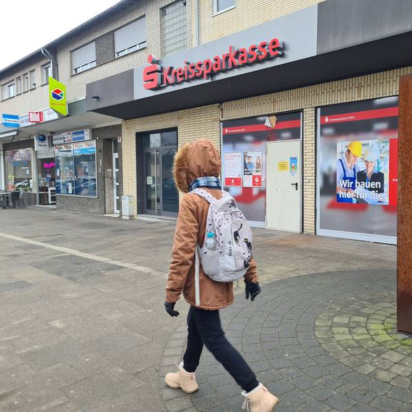 Eine Person mit Rucksack geht an einer geschlossenen Filiale der Kreissparkasse vorbei.
