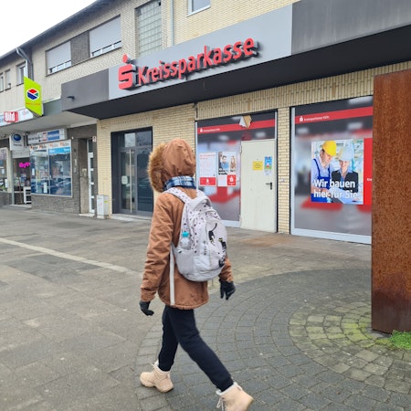 Eine Person mit Rucksack geht an einer geschlossenen Filiale der Kreissparkasse vorbei.