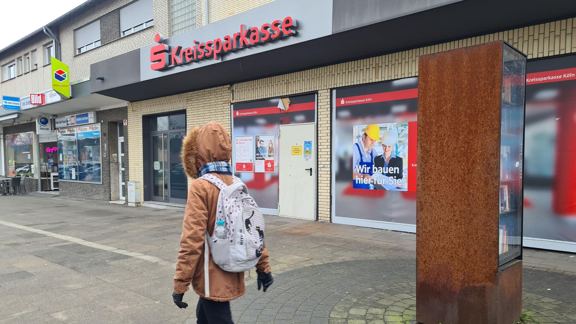 Eine Person mit Rucksack geht an einer geschlossenen Filiale der Kreissparkasse vorbei.