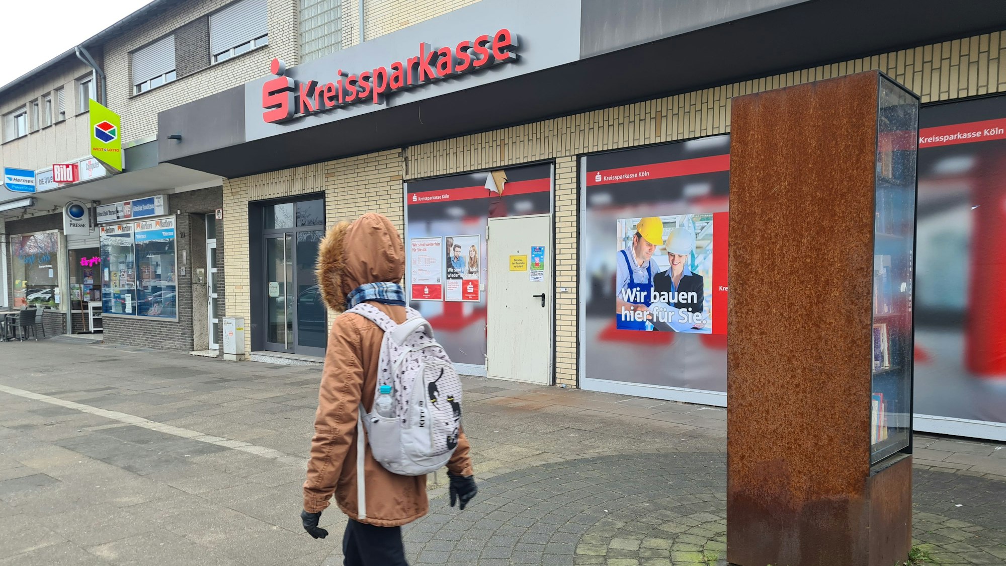 Eine Person mit Rucksack geht an einer geschlossenen Filiale der Kreissparkasse vorbei.