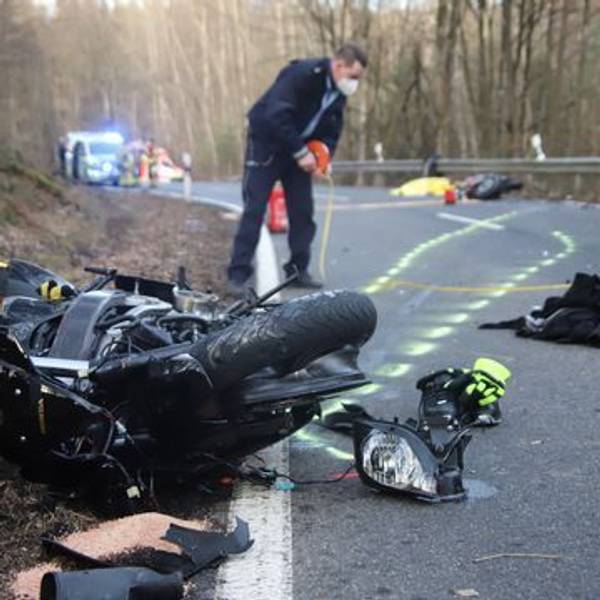 Nach einem Unfall in Much am 20. Februar 2021 liegen Teile eines Motorrads auf der Straße. Ein Polizist sichert die Szene.