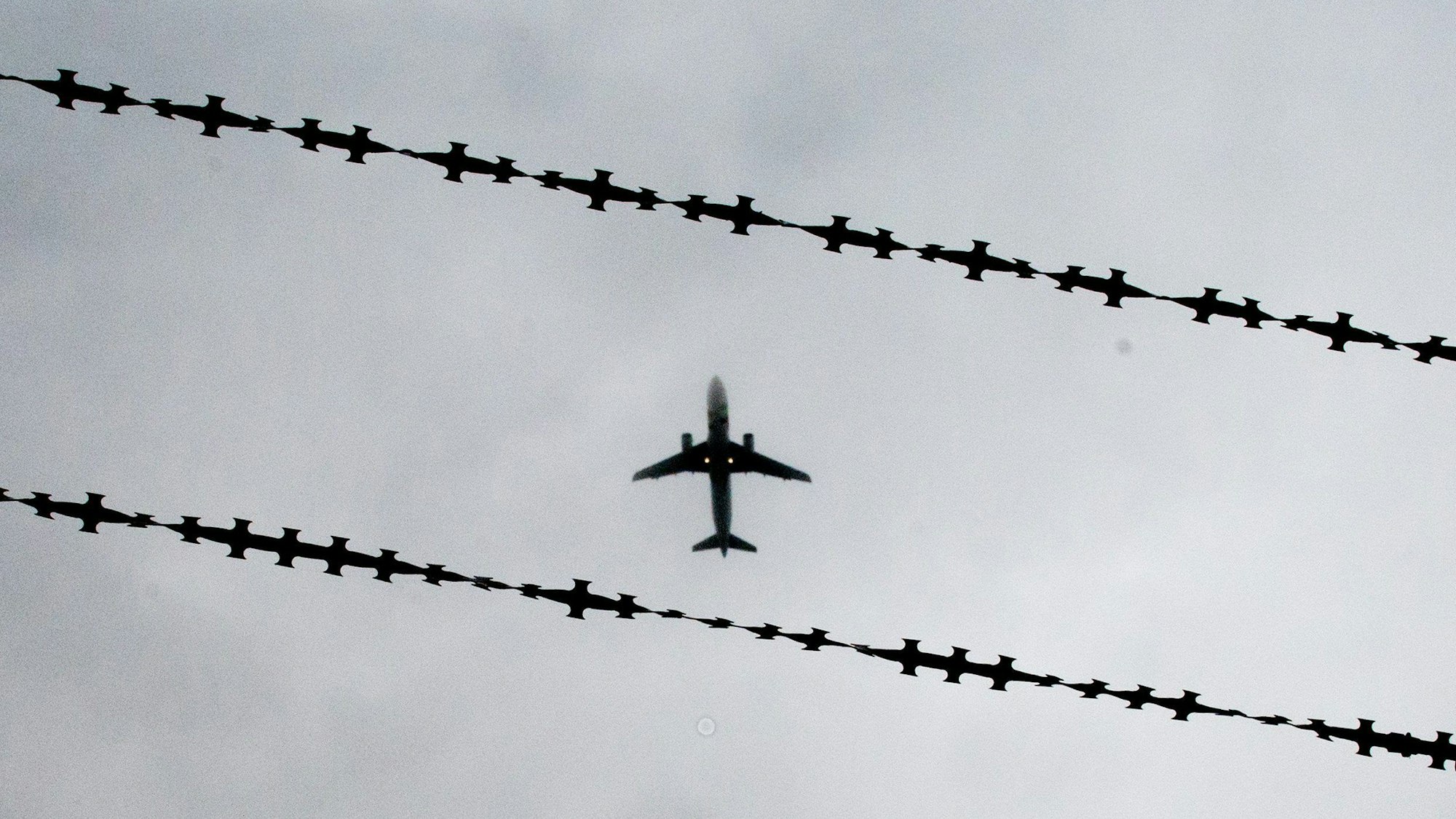 Ein Flugzeug ist hinter Stacheldraht zu sehen.