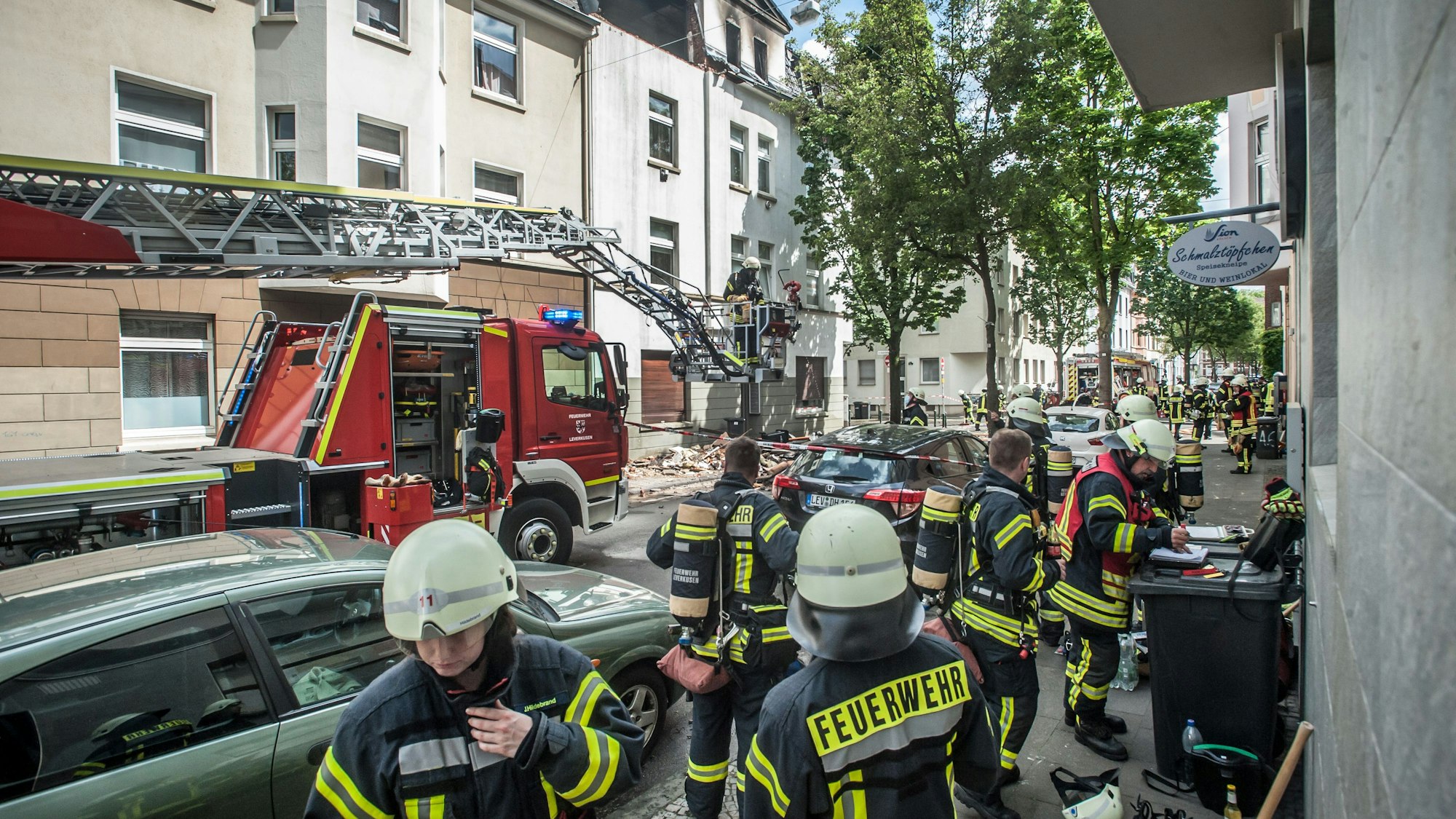Feuerwehrleute stehen am 13. Mai 2022 vor einem Haus auf der Augustastraße in Opladen.