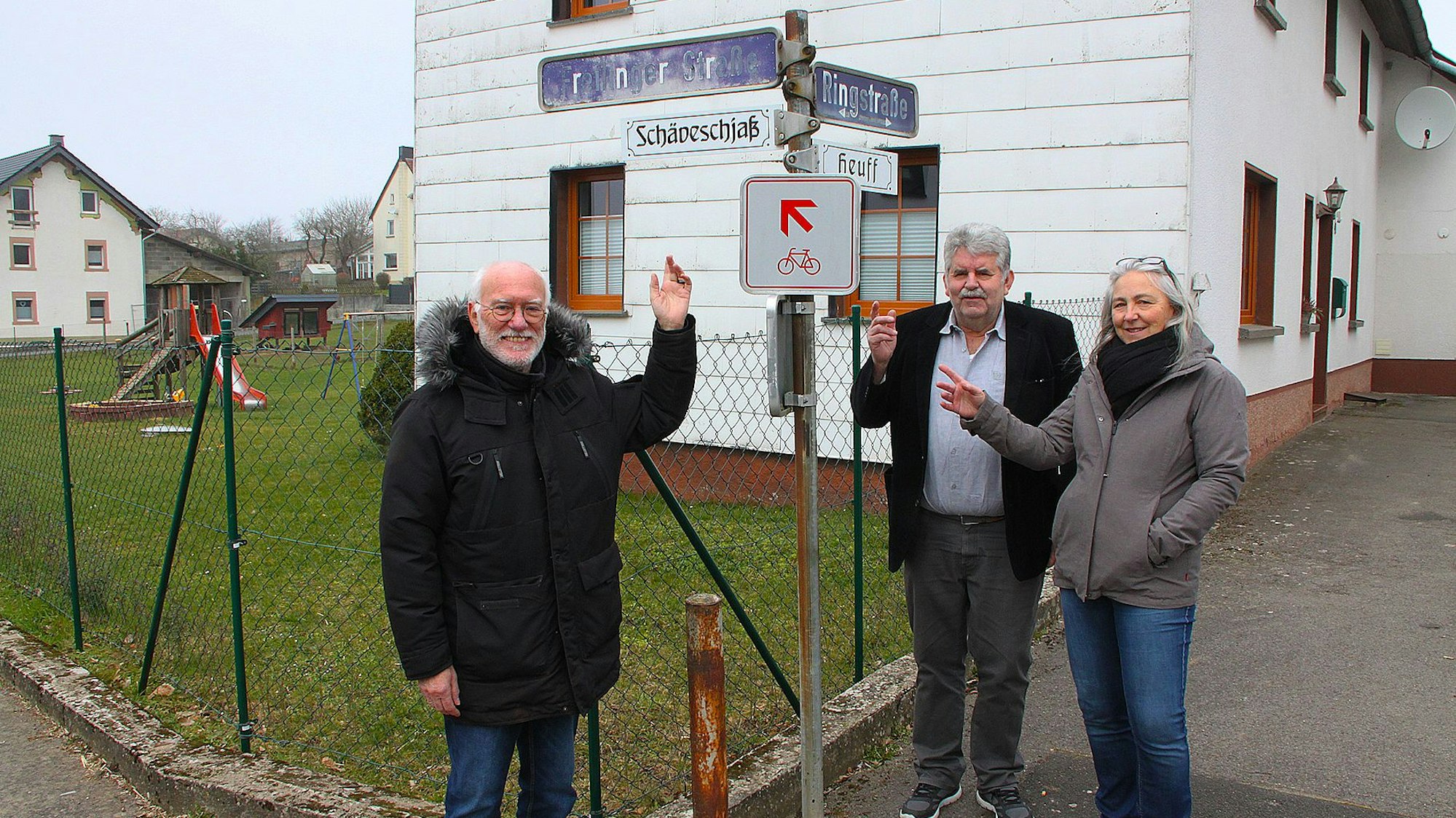 Elke Schomers, Peter Klippelt und Herbert Daniels stehen unter einem Straßenschild.