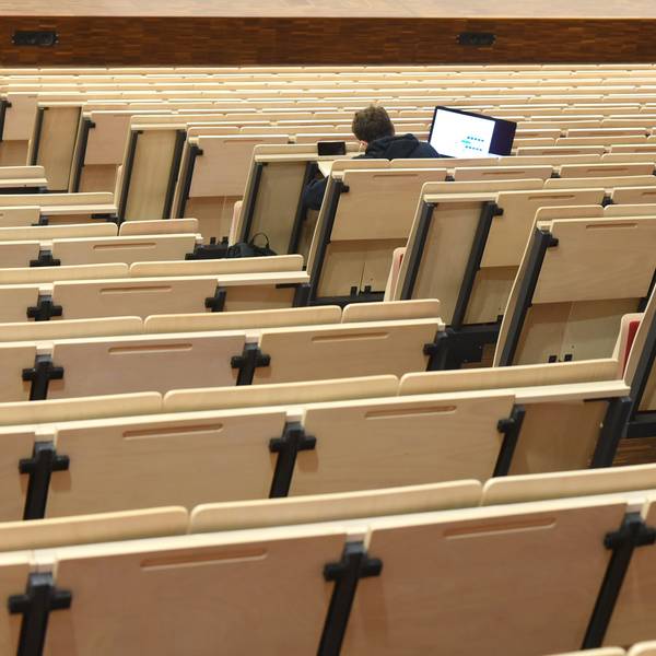 Ein Student sitzt in einem ansonsten leeren Vorlesungssaal.