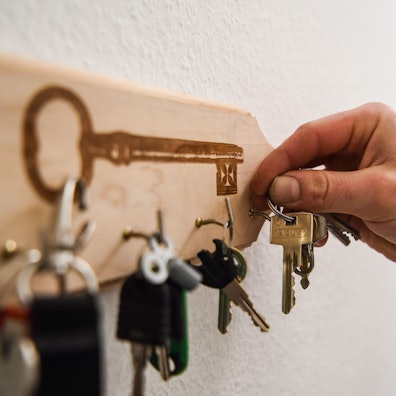 Ein Mann hängt einen Schlüsselbund an einen Haken am Schlüsselbrett an.