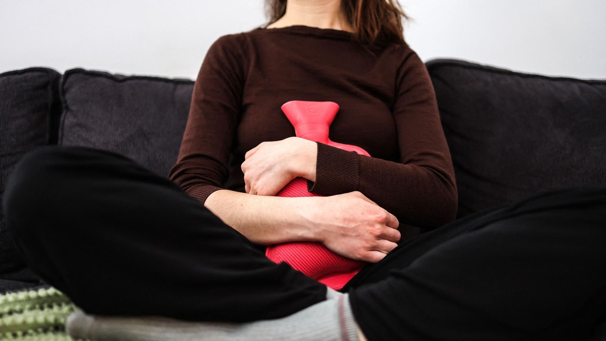 Eine Frau hält sich eine Wärmflasche auf den Bauch. In Frankreich sollen Frauen bis 25 Jahren nun kostenlos Perioden-Produkte erhalten. (Symbolbild)