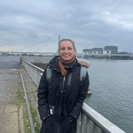 Die alleinerziehende Mutter Judith B. steht auf der Deutzer Werft, mit Blick auf die Kranhäuser am anderen Rheinufer.