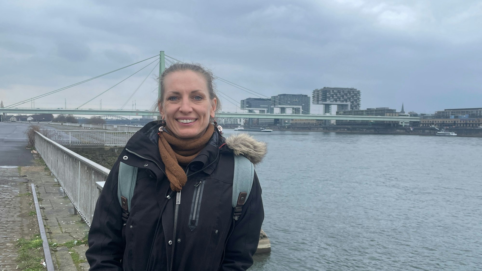 Die alleinerziehende Mutter Judith B. steht auf der Deutzer Werft, mit Blick auf die Kranhäuser am anderen Rheinufer.