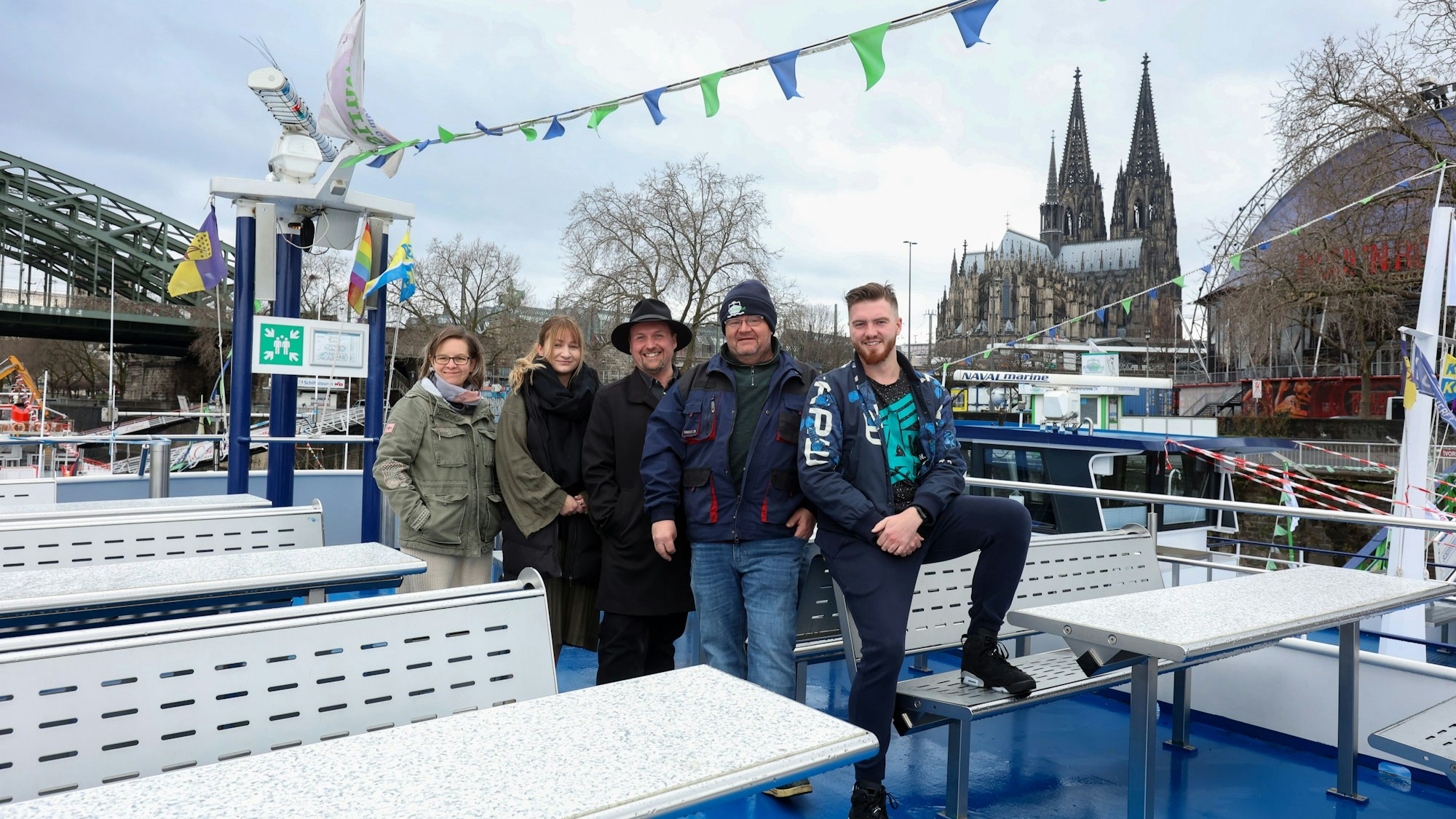 Das Team von Köln-Tourist auf dem Deck eines Schiffes, im Hintergrund der Dom und der Musical Dome