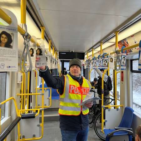 Kriminalhauptkommissar Ulrich Riepelmeier hängt Zettel mit Fahndungsaufrufen zum Cold Case Seckin Caglar in einer KVB-Bahn der Linie 7 auf.