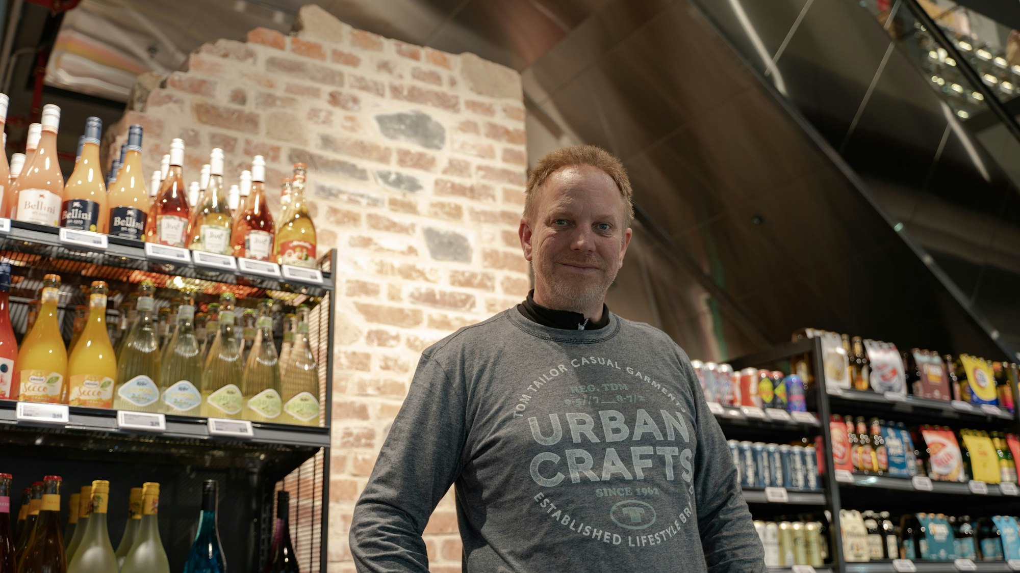 Filialleiter Markus Kelterbaum vor einem Teil der historischen Kölner Stadtmauer.