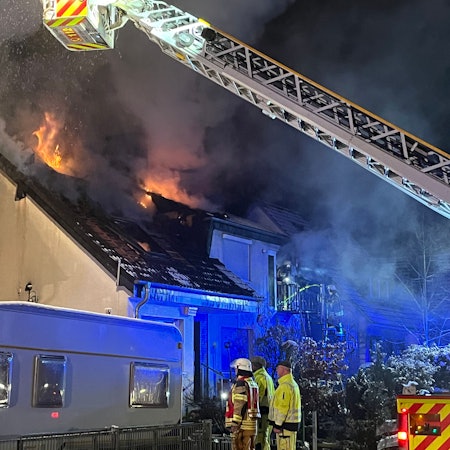 Feuer kommt aus den Fenstern im oberen Stockwerk eines Hauses