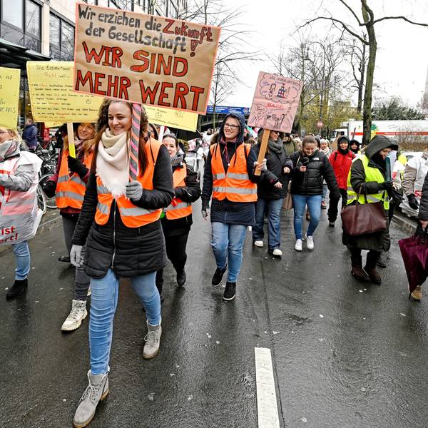Eine Demonstrantin trägt ein Schild mit der Aufschrift "Wir erziehen die Zukunft der Gesellschaft. Wir sind mehr wert!" auf einer Demo für mehr Lohn in Sozialberufen in Köln.