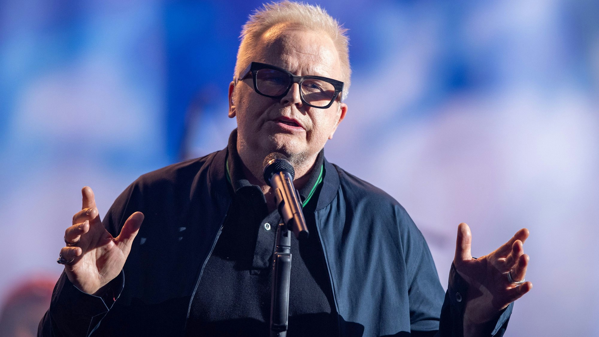 Der deutsche Sänger Herbert Grönemeyer steht auf einer Bühne.
