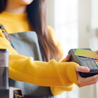 Eine Frau hält das Kartengerät und ein Mann zahlt mit seiner Karte.