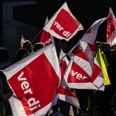 Teilnehmer stehen beim Jugendstreiktag mit Verdi-Fahnen auf einem Platz.