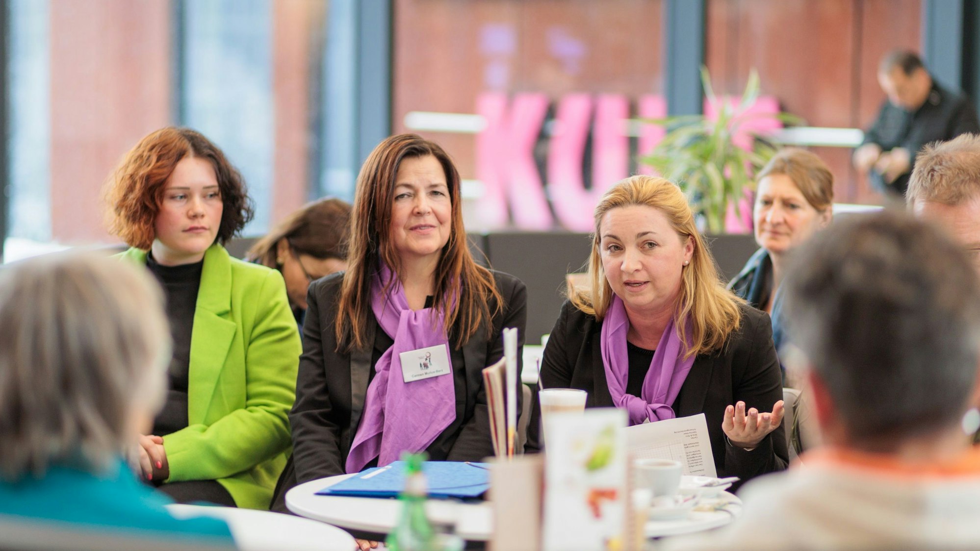 Drei Frauen sitzen bei einer Informationsveranstaltung nebeneinander.