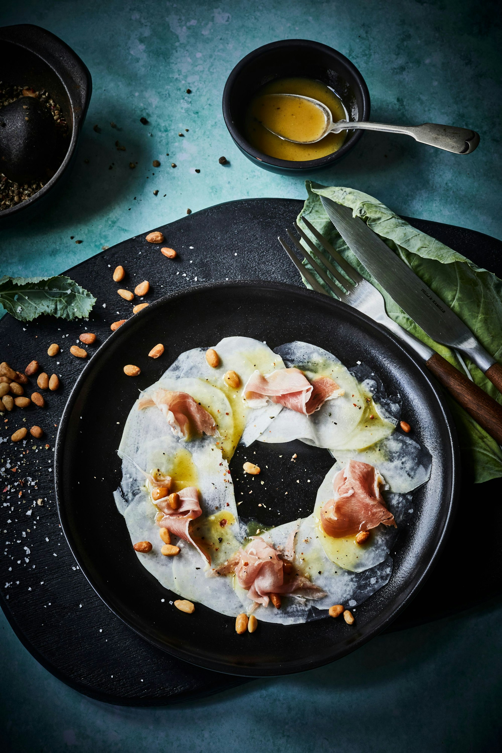 Die Kohlrabi-Carpaccio ist eine vegetarische Vorspeise, die aber wie auf dem Foto mit luftgetrocknetem Schinken ergänzt werden kann.