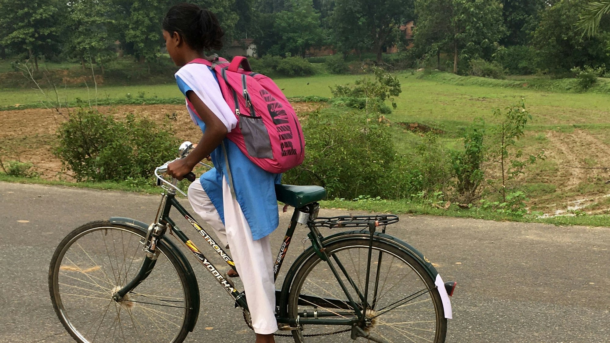 Ein Mädchen fährt auf ihrem Rad zur Schule.