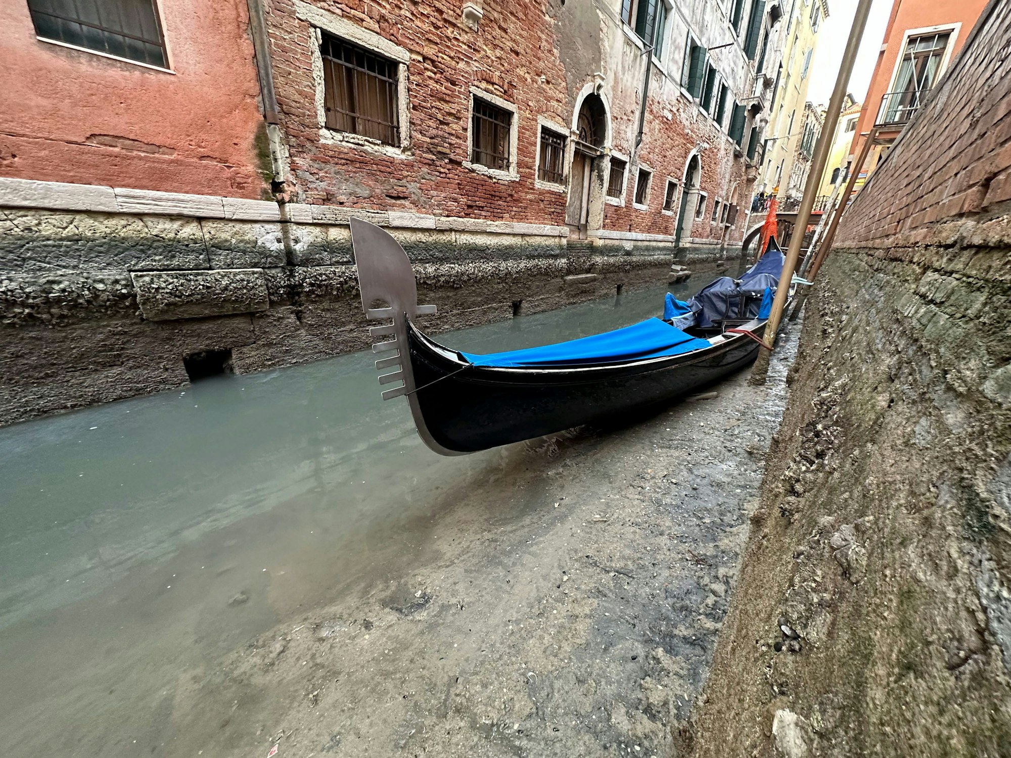 Italien, Venedig: Eine Gondel liegt bei Ebbe an einem Kanal.