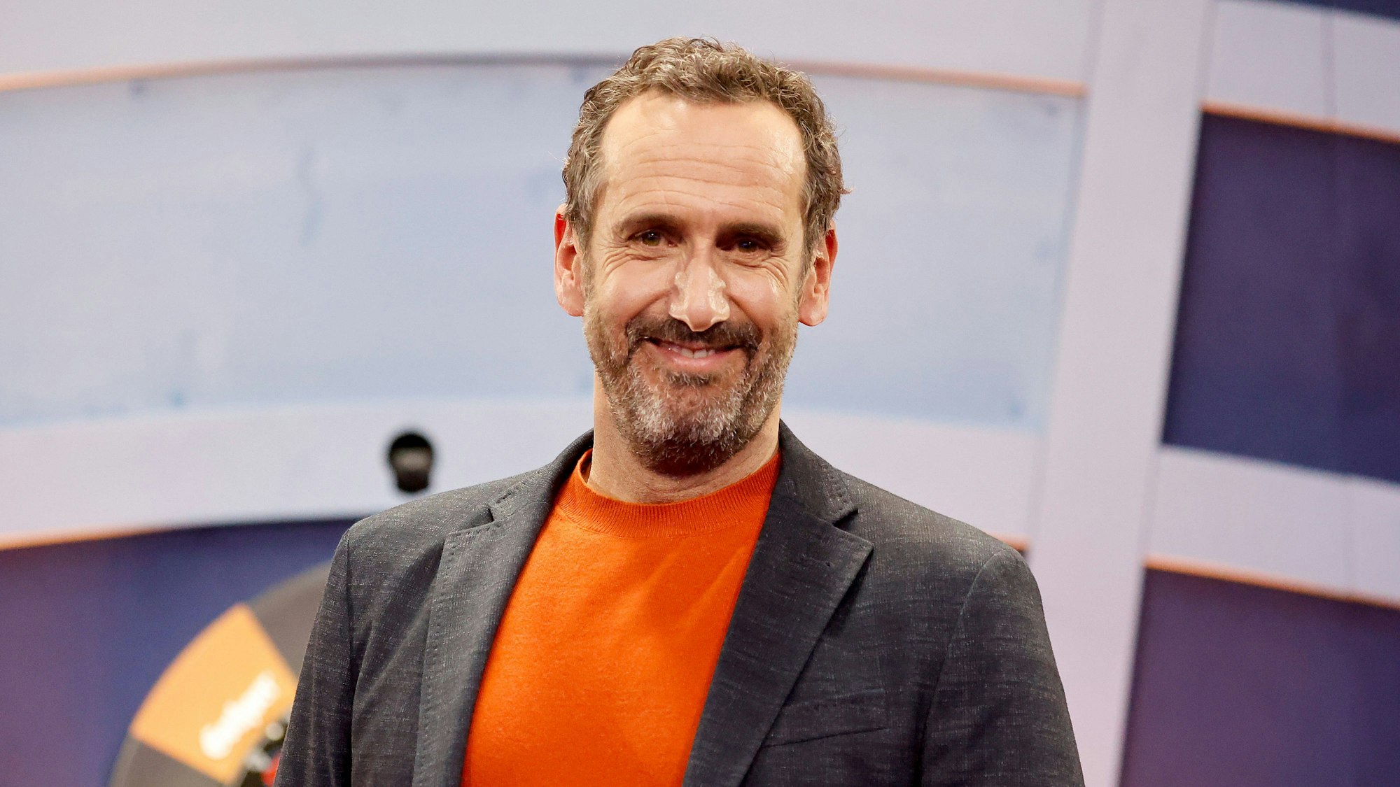 Elmar Paulke steht vor einer Dartscheibe.