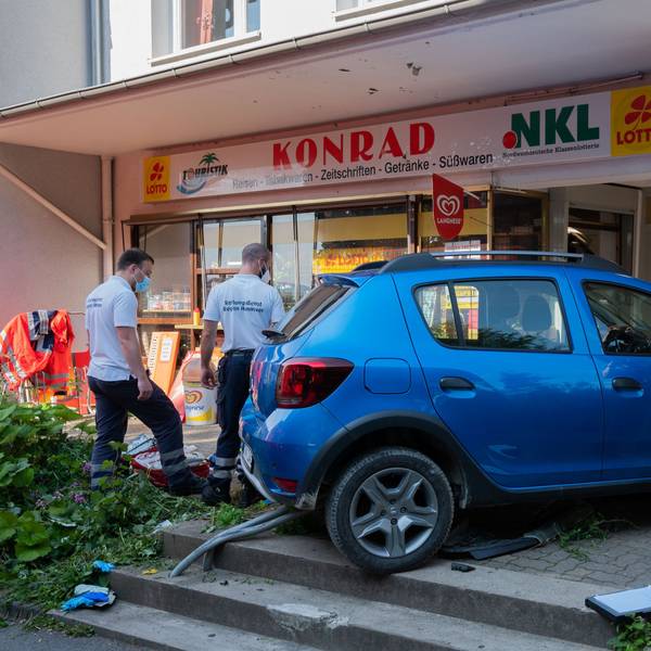 Einsatzkräfte von Rettungsdienst und Polizei stehen nach einem Unfall an einem Kleinwagen