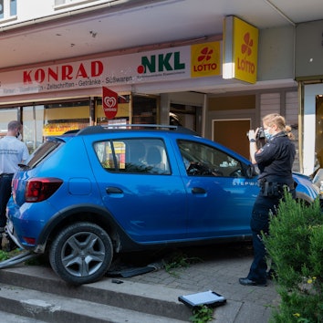 Einsatzkräfte von Rettungsdienst und Polizei stehen nach einem Unfall an einem Kleinwagen