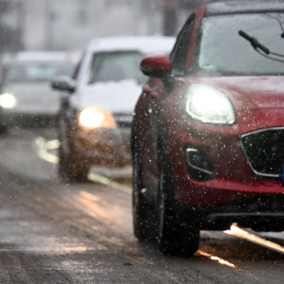 Radfahrer und Autos fahren durch den Schnee.