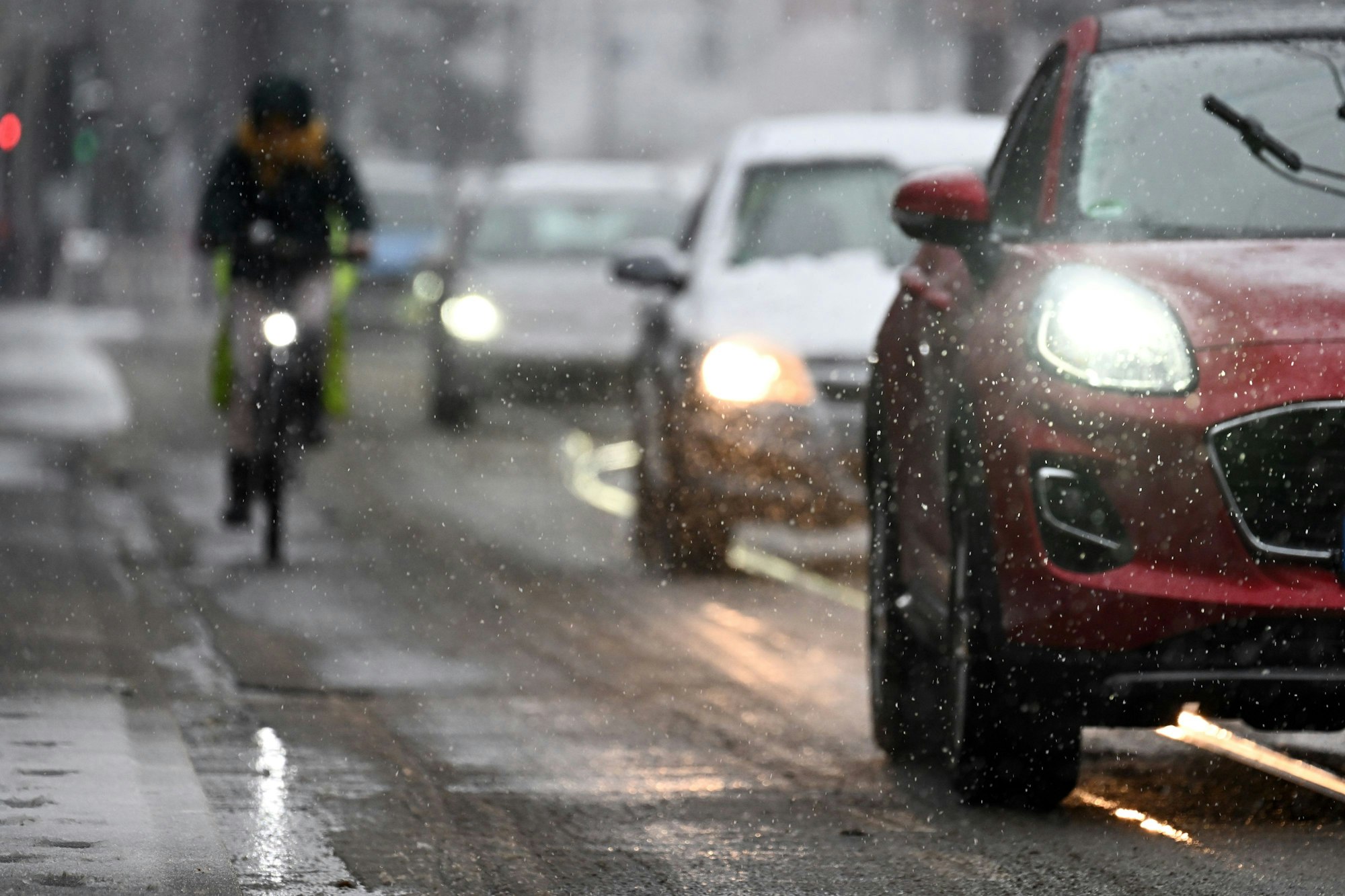 Radfahrer und Autos fahren durch den Schnee.