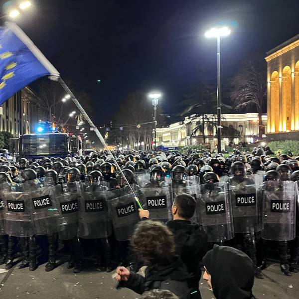 Ein Demonstrant, der eine EU-Flagge trägt, geht auf eine Polizeikette vor dem georgischen Parlamentsgebäude zu. Unter heftigem Protest aus der Bevölkerung ist in Georgien im Südkaukasus eine umstrittene Regelung über „ausländische Agenten“ auf den Weg gebracht worden.