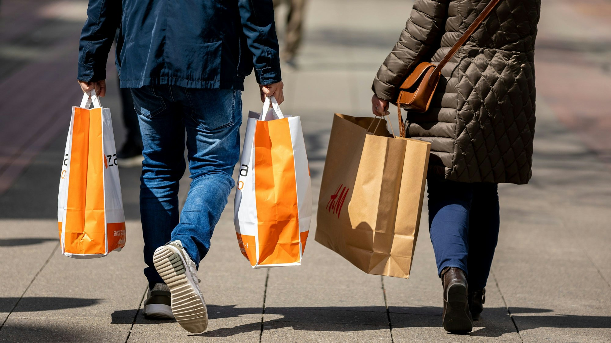 Passanten gehen mit Papiertüten in den Händen durch die Innenstadt. (Symbolbild)