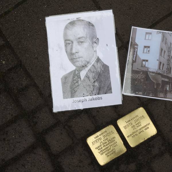 Neben zwei Stolpersteinen in Gedenken an Joseph und Berta Jakobs liegen zwei Bilder. Ein Porträt von Joseph und ein Bild von seinem Schuhgeschäft auf der Venloer Straße.