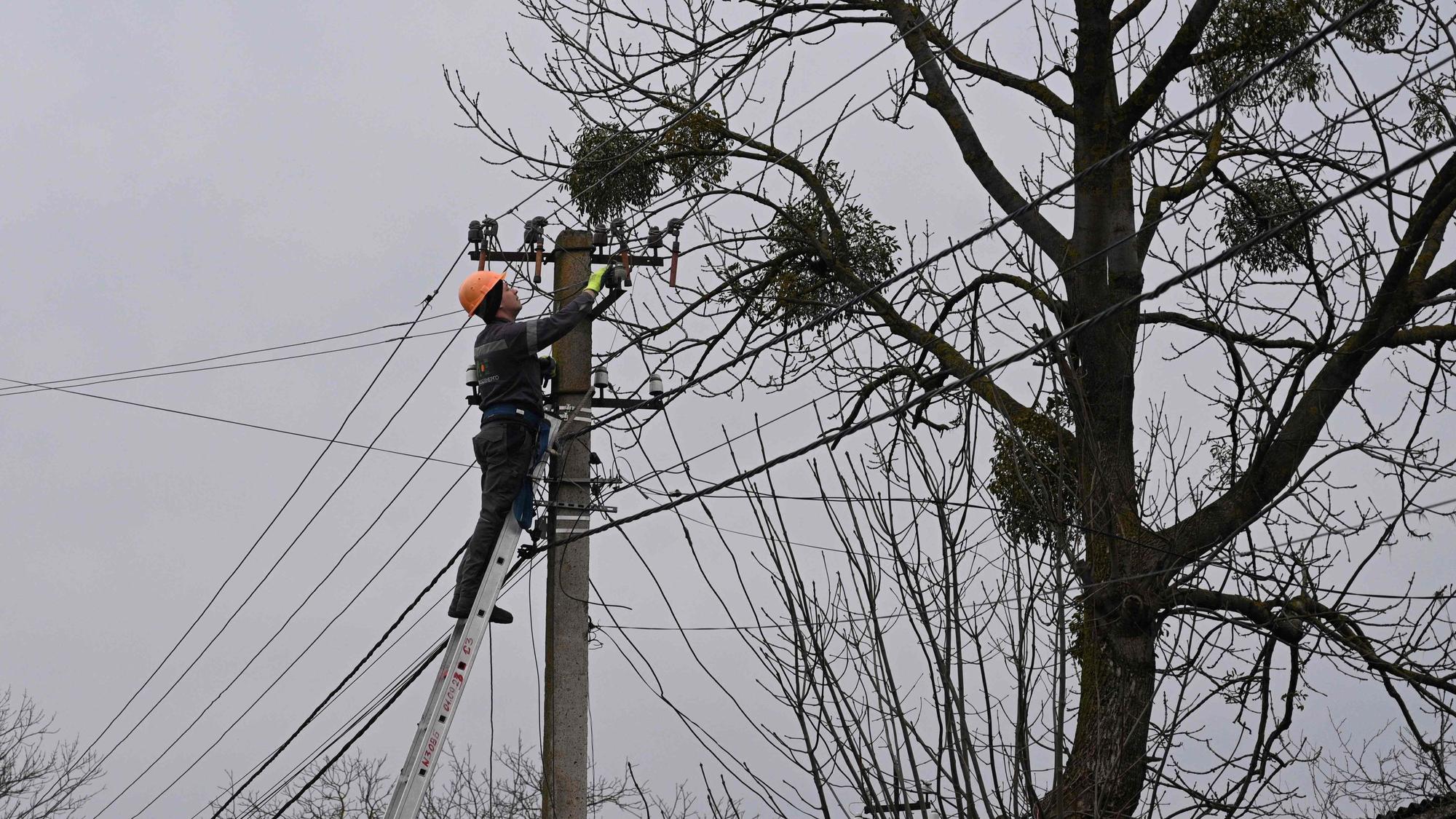 Ein Arbeiter repariert nach einem russischen Angriff eine Stromleitung in einem Dorf in der Nähe der ukrainischen Stadt Lwiw.