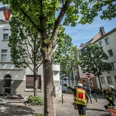 Feuerwehrleute zeigen auf ein brennendes Haus in Opladen.