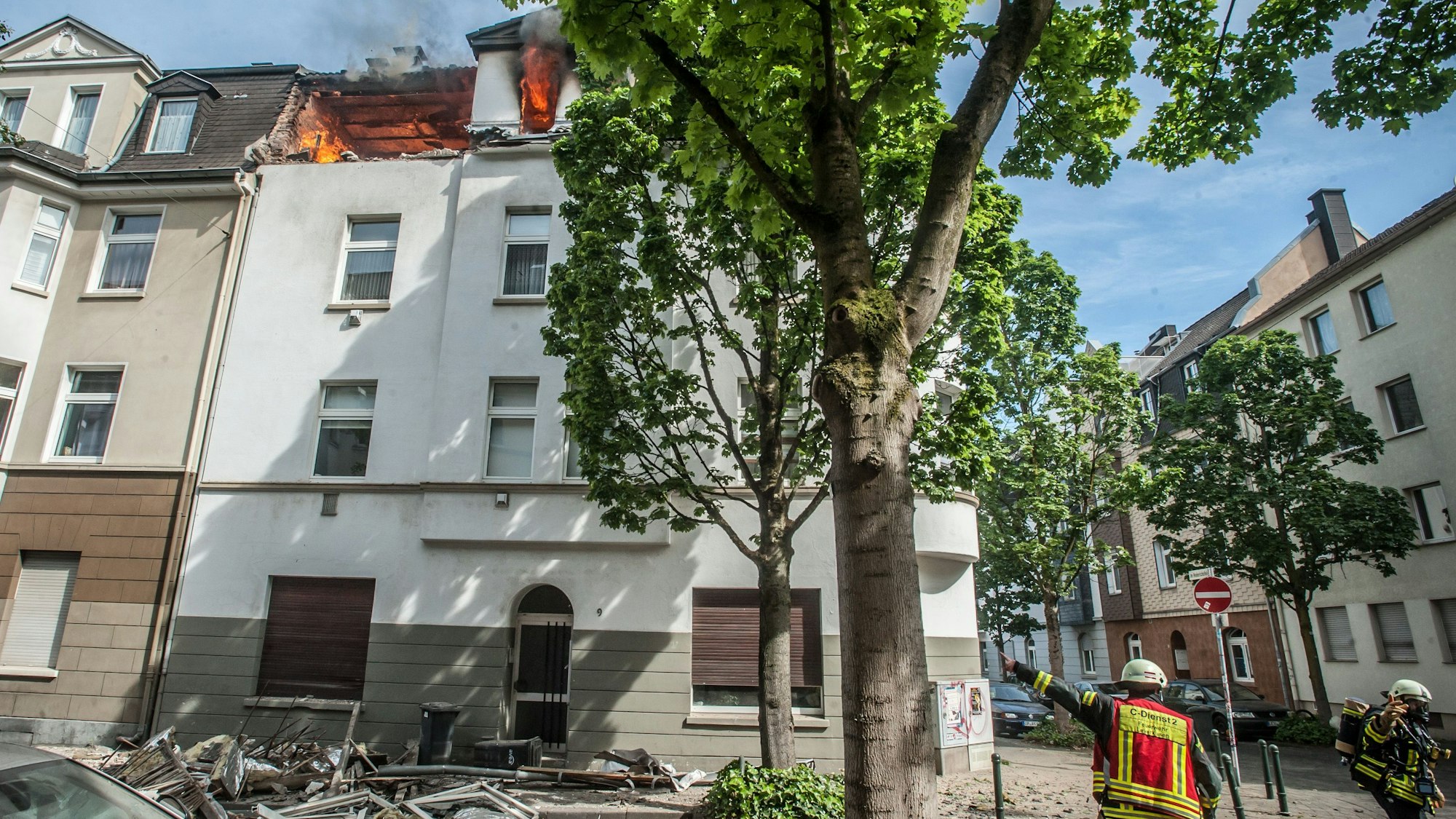 Feuerwehrleute zeigen auf ein brennendes Haus in Opladen.