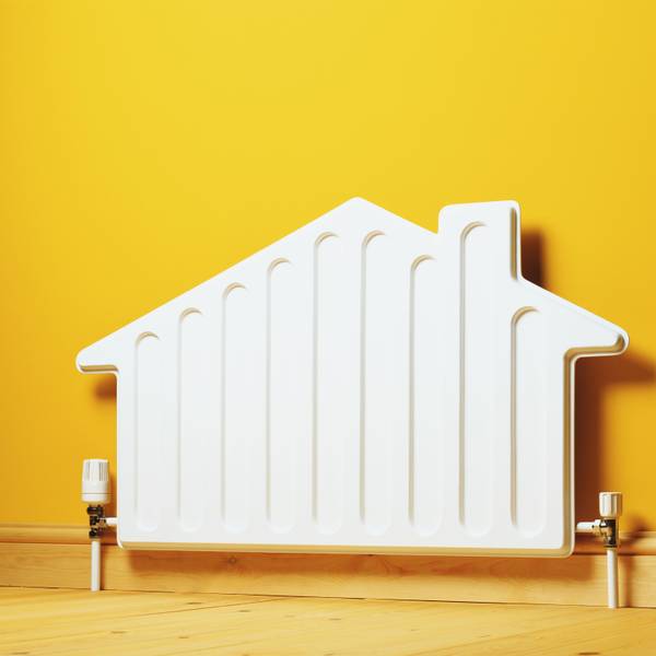 Ein Heizkörper in der Form eines Hauses steht vor einer gelben Wand.