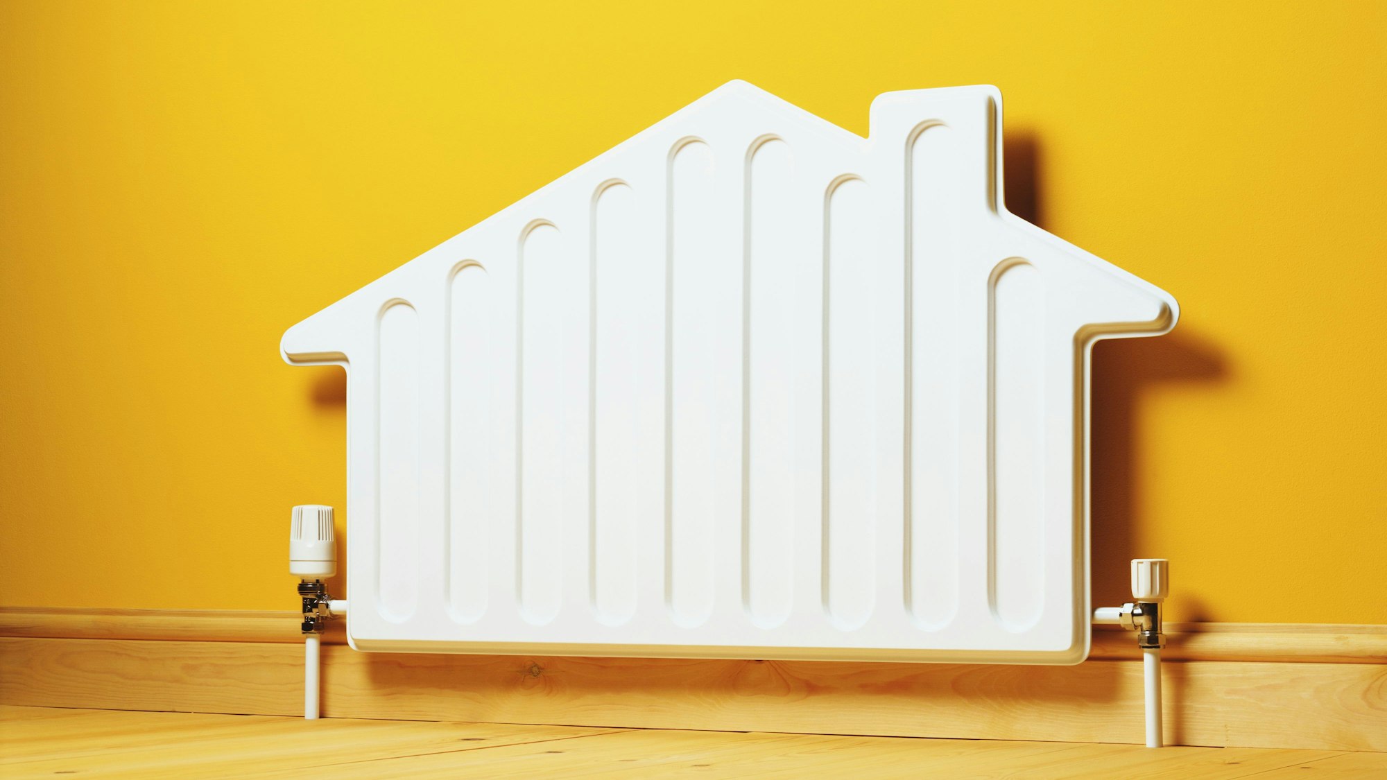 Ein Heizkörper in der Form eines Hauses steht vor einer gelben Wand.