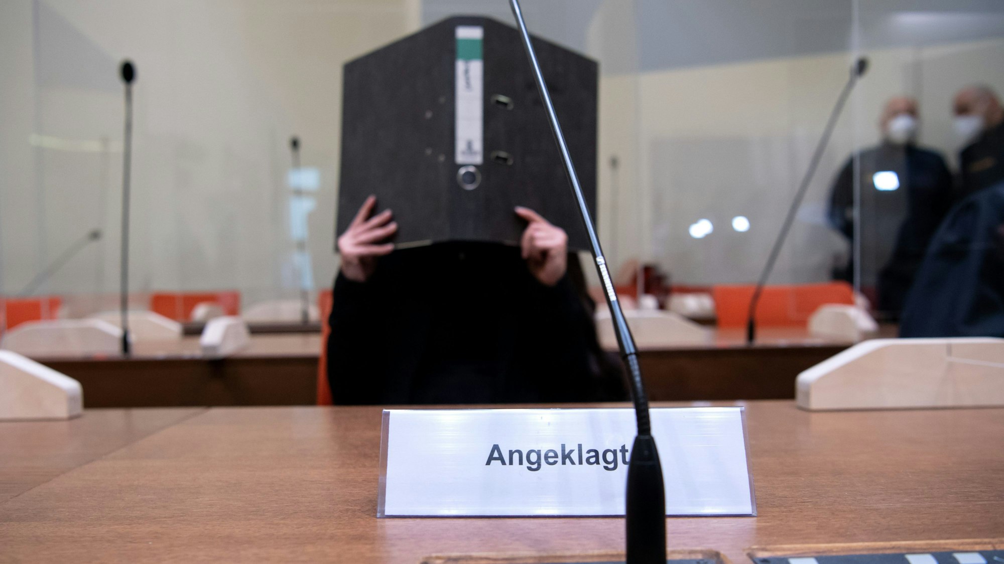 Die Angeklagte Jennifer W. im Oktober 2021 im Gerichtssaal in München. Sie hält sich einen Ordner vors Gesicht.