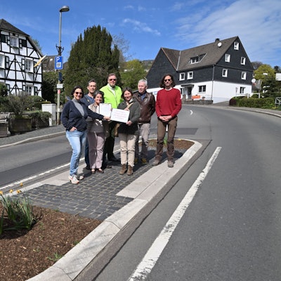 Mehrere Menschen stehen auf einer Fußgängerinsel.
