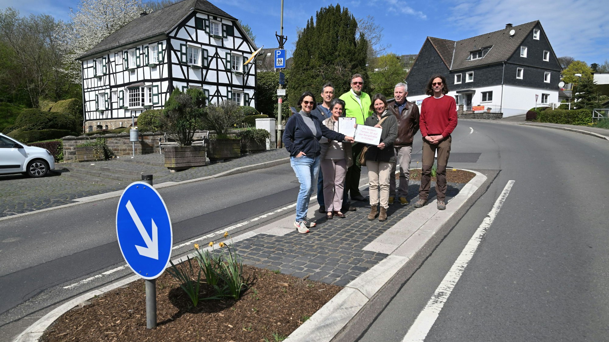 Mehrere Menschen stehen auf einer Fußgängerinsel.